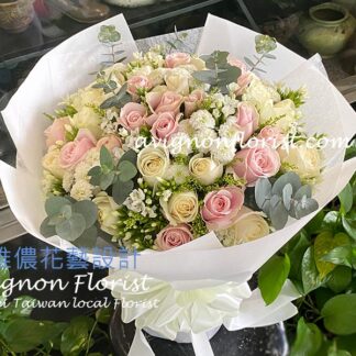 Wrapped bouquet of white and pink roses with soft accent flowers, styled in a modern romantic design.