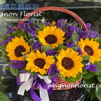 黃色向日葵搭配紫色系花材的桌上型花籃，整體感覺明亮溫暖、自然親切